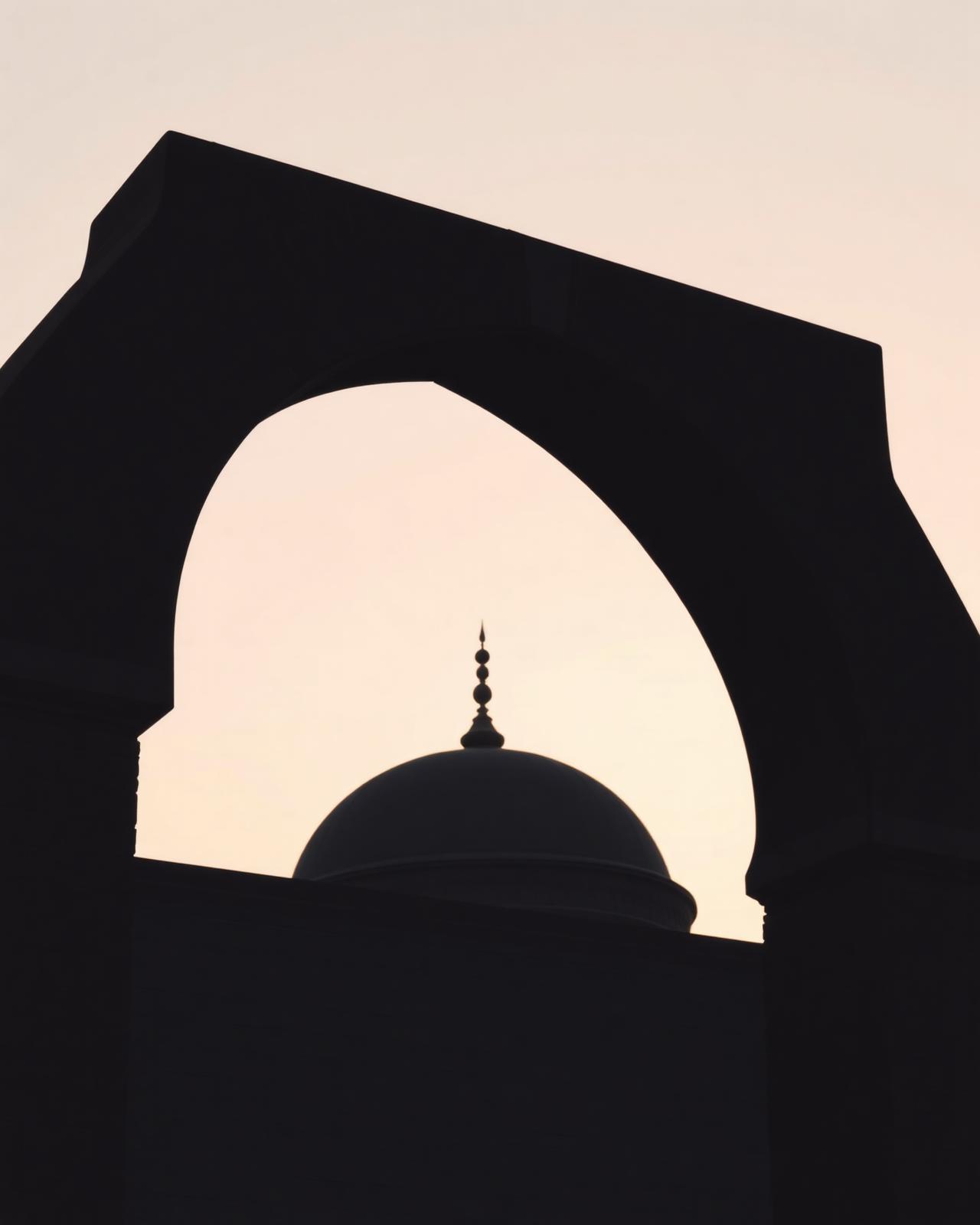 A mosque dome and arch silhouetted at dawn